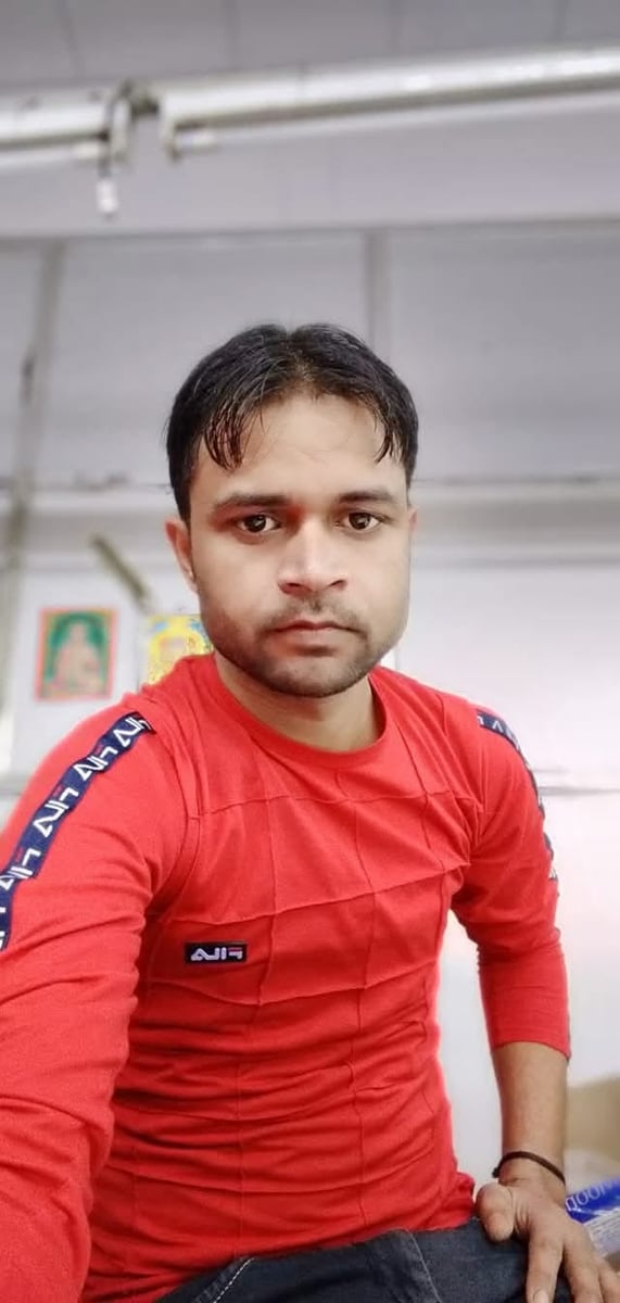 Amit in a casual portrait wearing a red long-sleeve shirt